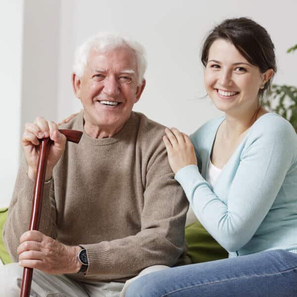 companion senior caregiver smiling with an elderly man with white hair